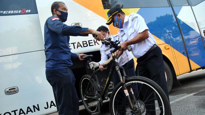 Pekerja pengguna sepeda bersama petugas menaikkan sepeda ke dalam bagasi bus di pool bus Damri, Botani Square, Kota Bogor, Jawa Barat, Senin (20/7/2020).  [ANTARA FOTO/Arif Firmansyah]