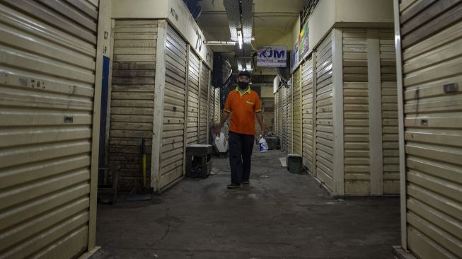 Petugas kebersihan berjalan di depan toko yang tutup di Pasar Asem Reges, Jakarta Barat, Selasa (21/7/2020). [ANTARA FOTO/Nova Wahyudi]