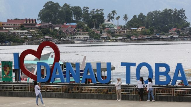 Pengunjung berfoto berlatar Danau Toba di Parapat, Sumatera Utara, Indonesia pada 21 Juli 2020. [Foto/Anadolu Agency