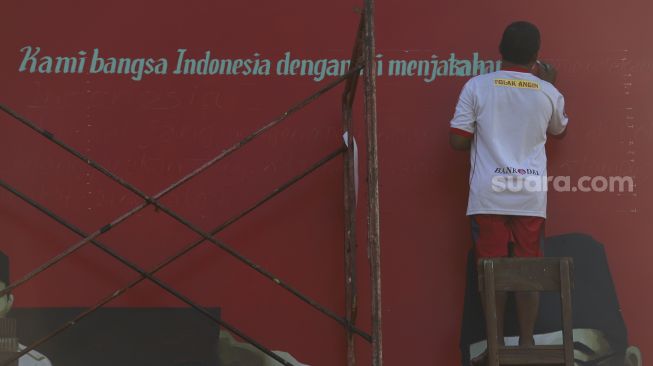 Pekerja menyelesaikan mural bertemakan Proklamasi di Sekolah Dasar Negeri (SDN) Pondok Aren 02, Tangerang Selatan, Banten, Rabu (22/7/2020). [Suara.com/Angga Budhiyanto]