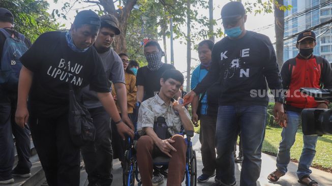 Rekan - rekan media membantu mendorong kursi roda El Ibnu vokalis band Elkasih saat ditemui di Kawasan Tandean, Jakarta Selatan, Rabu (22/7). [Suara.com/Alfian Winanto]