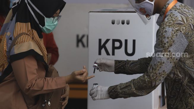 Petugas meneteskan tinta kepada pemilih usai melakukan pencoblosan saat simulasi pemungutan suara Pilkada Serentak 2020 di Kantor Komisi Pemilihan Umum (KPU) Republik Indonesia, Jakarta, Rabu (22/72020). [Suara.com/Angga Budhiyanto]