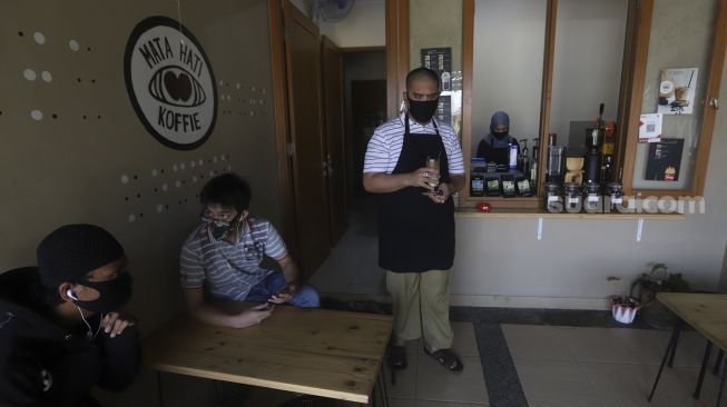 Ahmad Hilmy Almusawa (22) penyandang tunanetra mengantarkan kopi pesanan pelanggan di Mata Hati Koffie di Pondok Cabe Ilir, Pamulang, Tangerang Selatan, Banten, Kamis (23/7/2020). [Suara.com/Angga Budhiyanto]