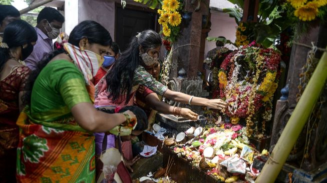 Umat Hindu memberikan persembahan kepada patung-patung ular pada kesempatan Nag Panchami untuk pemujaan tradisional dewa ular di Sri Manasa Devi dan kuil Nagadevata di Secunderabad, kota kembar Hyderabad, India, Sabtu (25/7/2020). [NOAH SEELAM / AFP]
