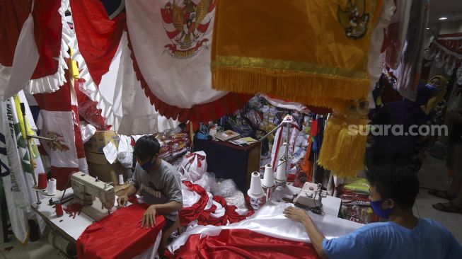 Pekerja menyelesaikan pembuatan pernak-pernik Bendera Republik Indonesia di Pasar Senen, Jakarta, Minggu (26/7/2020). [Suara.com/Angga Budhiyanto]