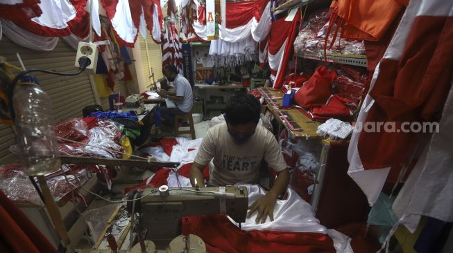 Pekerja menyelesaikan pembuatan pernak-pernik Bendera Republik Indonesia di Pasar Senen, Jakarta, Minggu (26/7/2020). [Suara.com/Angga Budhiyanto]