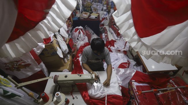 Pekerja menyelesaikan pembuatan pernak-pernik Bendera Republik Indonesia di Pasar Senen, Jakarta, Minggu (26/7/2020). [Suara.com/Angga Budhiyanto]