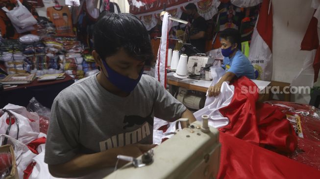 Pekerja menyelesaikan pembuatan pernak-pernik Bendera Republik Indonesia di Pasar Senen, Jakarta, Minggu (26/7/2020). [Suara.com/Angga Budhiyanto]