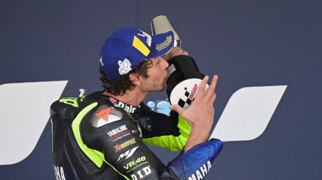 Pebalap Monster Energy Yamaha Valentino Rossi mencium trofi usai finis di posisi tiga MotoGP Andalusia, Spanyol, Minggu (26/7/2020). [AFP]