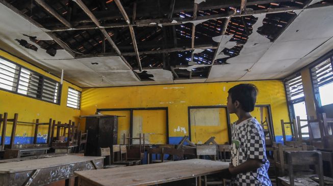 Seorang anak mengamati ruang kelas SDN Mekarsari 05 yang kondisi bangunannya rusak di Tambun, Kabupaten Bekasi, Jawa Barat, Senin (27/7/2020). [ANTARA FOTO/Fakhri Hermansyah]