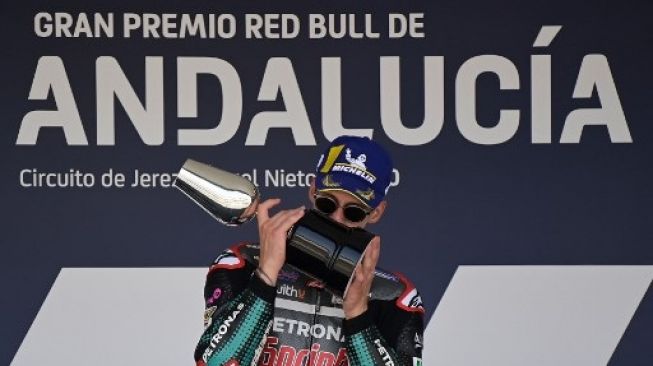 Pebalap Petronas Yamaha SRT Fabio Quartararo mencium trofi di podium setelah menjadi juara MotoGP Andalusia. JAVIER SORIANO / AFP