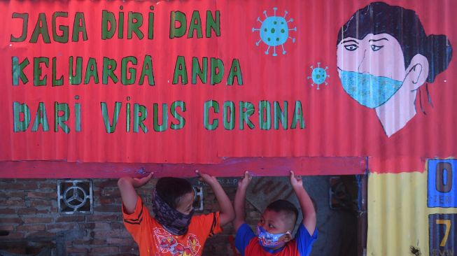 Seorang anak bermain di samping mural bertema COVID-19 di Jakarta, Senin (27/7/2020).  [ANTARA FOTO/Akbar Nugroho Gumay]
