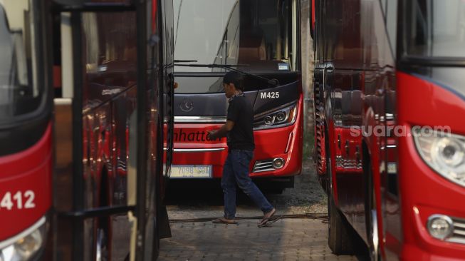 Seorang mekanik meninjau bus yang terparkir di salah satu pool bus pariwisata di kawasan Tanjung Barat, Jagakarsa, Jakarta, Selasa (28/7/2020). [Suara.com/Angga Budhiyanto]