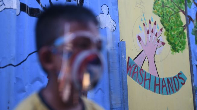 Seorang anak melintasi mural bertema COVID-19 di Jakarta, Senin (27/7/2020). [ANTARA FOTO/Akbar Nugroho Gumay]