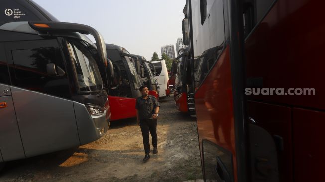 Petugas meninjau bus yang terparkir di salah satu pool bus pariwisata di kawasan Tanjung Barat, Jagakarsa, Jakarta, Selasa (28/7/2020). [Suara.com/Angga Budhiyanto]