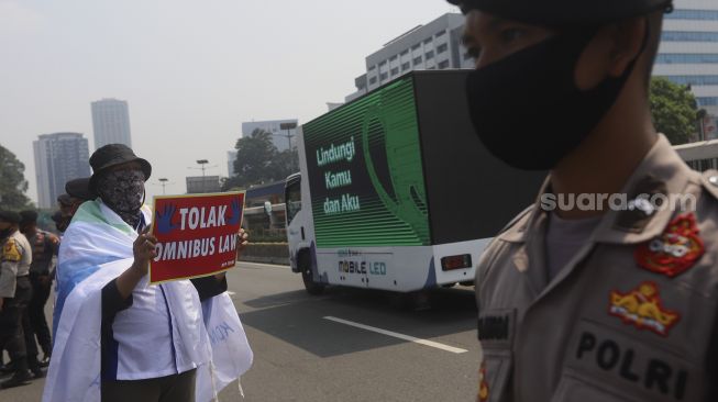 Massa buruh yang tergabung dalam Konfederasi Serikat Pekerja Indonesia ( KSPI) membawa poster saat mengelar aksi unjuk rasa di depan Gedung DPR, Jakarta, Rabu (29/7/2020). [Suara.com/Angga Budhiyanto]