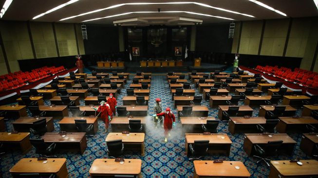 Petugas menyemprotkan cairan disinfektan di ruang sidang paripurna DPRD DKI Jakarta, Rabu (29/7/2020). [ANTARA FOTO/Rivan Awal Lingga]