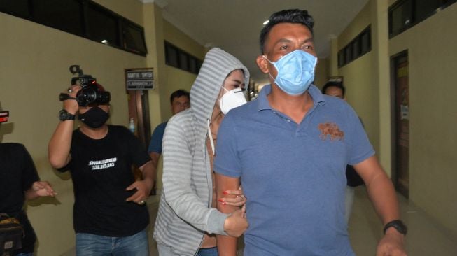 Personel kepolisian membawa artis berinisial VS (tengah) saat akan menjalani pemeriksaan di Polresta Bandar Lampung, Lampung, Rabu (29/7/2020).  [ANTARA FOTO/ Ardiansyah]