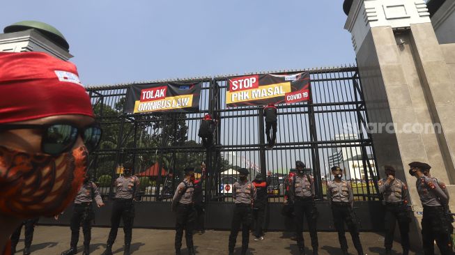 Sejumlah massa buruh yang tergabung dalam Konfederasi Serikat Pekerja Indonesia ( KSPI) memasang spanduk saat mengelar aksi unjuk rasa di depan Gedung DPR, Jakarta, Rabu (29/7/2020). [Suara.com/Angga Budhiyanto]