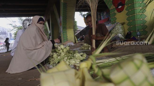 Pedagang kulit ketupat melayani pembeli di bawah jalan tol di kawasan Bintaro, Jakarta, Kamis (30/7/2020). [Suara.com/Angga Budhiyanto]