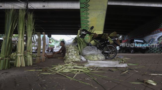 Pedagang kulit ketupat menunggu pembeli di bawah jalan tol di kawasan Bintaro, Jakarta, Kamis (30/7/2020). [Suara.com/Angga Budhiyanto]