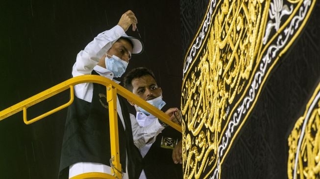 Pekerja memasang Kiswah Ka'bah yang baru yang terbuat dari kain sutra hitam dan benang emas serta disulam dengan ayat-ayat suci Alquran, Mekah, Arab Saudi, Rabu (29/7).  [Foto/AFP]