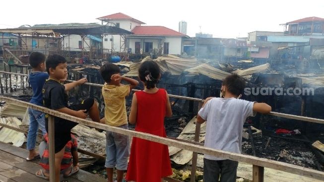 Anak-anak menyaksikan sisa bangunan akibat kebakaran yang terjadi pada Kamis (30/7/2020) dini hari tadi. [Suara.com/Bobi]