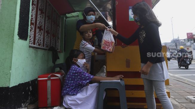 Siswi kelas 2 SDN 01 Pagi Bukit Duri Keysha Nayara Effeni (8) belajar secara online di gerai makanan tempat Ibunya berjualan di kawasan Bukit Duri, Jakarta, Kamis (30/7/2020). [Suara.com/Angga Budhiyanto]