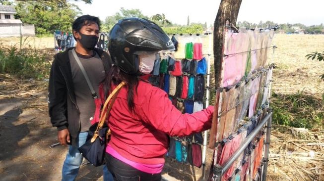 Pedagang masker asal Yogyakarta, Samhidayah (jaket hitam), menata masker di Jalan Imogiri Barat, Desa Sumberagung, Jetis, Bantul, Minggu (2/8/2020). - (SuaraJogja.id/Muhammad Ilham Baktora)