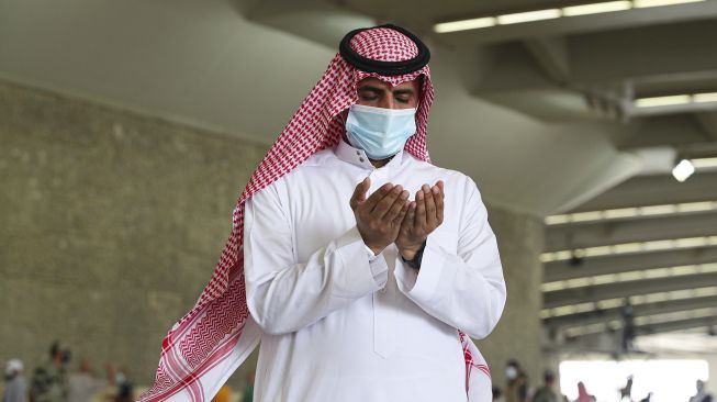 Jemaah haji berdoa usai melangsungkan lontar jumrah dengan mengenakan masker wajah untuk menghindari penularan COVID-19 di Mina, Arab Saudi, Sabtu (1/8/2020). [AFP]