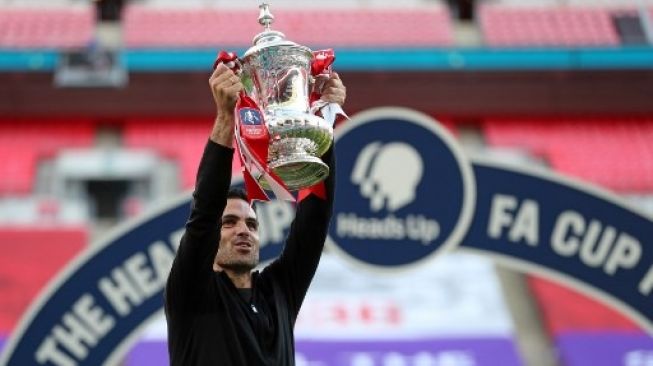 Manajer Arsenal Mikel Arteta mengangkat trofi Piala FA setelah skuatnya mengalahkan Chelsea saat  final di Wembley Stadium, London. Catherine Ivill / POOL / AFP