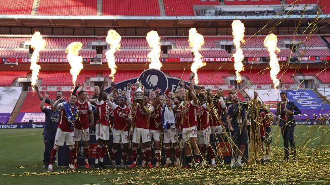 Striker Arsenal, Pierre-Emerick Aubameyang memegang trofi saat merayakan kemenangan dengan tim setelah memenangkan pertandingan final Piala FA Inggris antara Arsenal melawan Chelsea di  Wembley Stadion, London, Sabtu (1/8/2020). [Catherine Ivill / POOL / AFP]