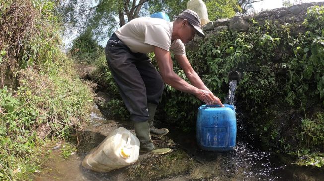 Warga Sungai Jambu mengisi air ke jerigen dari sumber mata air di kaki Gunung Kerinci, Kayu Aro Barat, Kerinci, Jambi, Minggu (2/8/2020).  [ANTARA FOTO/Wahdi Septiawan]