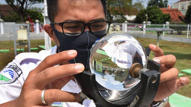 Petugas Badan Meteorologi, Klimatologi dan Geofisika (BMKG) memeriksa alat pengukur intensitas dan durasi penyinaran matahari (Campbell Stokes) di Laboratorium BMKG Serang, Banten, Senin (3/8/2020).  [ANTARA FOTO/Asep Fathulrahman]