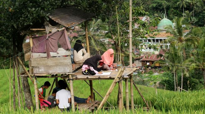 Sejumlah siswa SMA mengikuti kegiatan belajar mengajar dalam jaringan (daring) di area persawahan Bassaran, Desa Rante Mario, Kabupaten Enrekang, Sulawesi Selatan, Senin (3/8/2020).   [ANTARA FOTO/Arnas Padda]