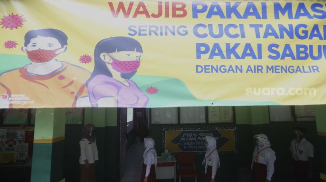 Sejumlah siswa mengantre sebelum memasuki ruang kelas di SDN Pekayon Jaya VI, Kota Bekasi, Jawa Barat, Selasa (4/8/2020). [Suara.com/Angga Budhiyanto]