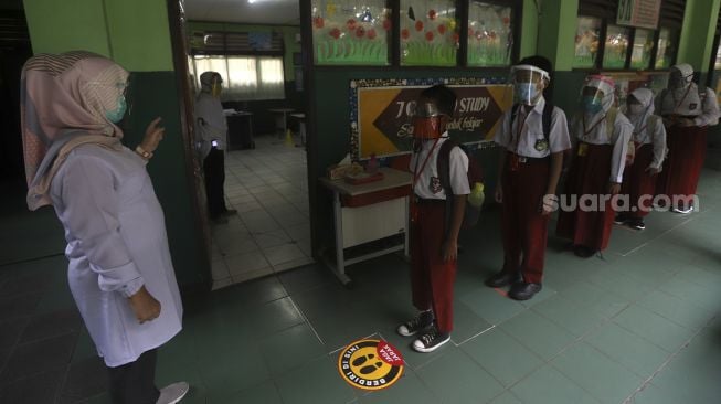 Sejumlah siswa mengantre sebelum memasuki ruang kelas di SDN Pekayon Jaya VI, Kota Bekasi, Jawa Barat, Selasa (4/8/2020). [Suara.com/Angga Budhiyanto]