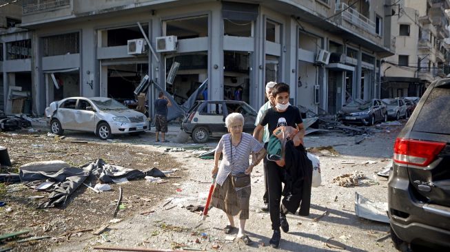 Seorang anak muda mengevakuasi orang tua saat ledakan besar di wilayah pelabuhan Beirut, Lebanon, Selasa (5/8/2020). [Foto/AFP]