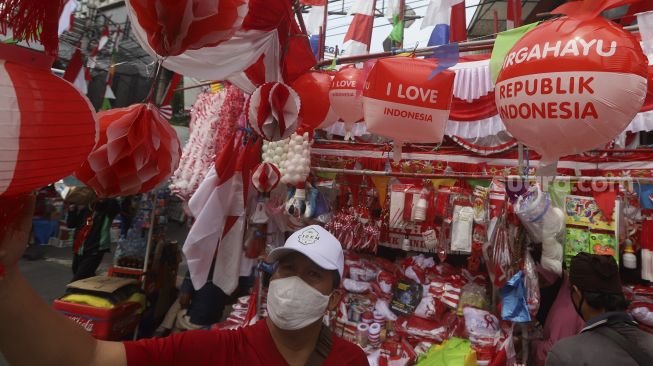 Seorang calon pembeli memilih pernak-pernik kemerdekaan di Pasar Jatinegara, Jakarta, Rabu (5/8/2020). [Suara.com/Angga Budhiyanto]