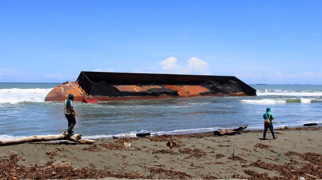 Warga melihat kapal tongkang pengangkut batu bara yang terdampar di Kawasan Pantai Naga Permai Desa Gampong Lhok, Kecamatan Kuala Pesisir, Nagan Raya, Aceh, Jumat (7/8/2020).  [ANTARA FOTO/Syifa Yulinnas]