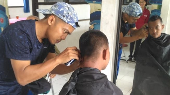 Capster memangkas rambut siswa SLB dalam program Baksos Cukur Rambut yang diinisiasi oleh pemilik Barbershop Cukur_Disini, Wahyu Kartiko Condro. - (SuaraJogja.id/HO-dok ist Wahyu Kartiko Condro)