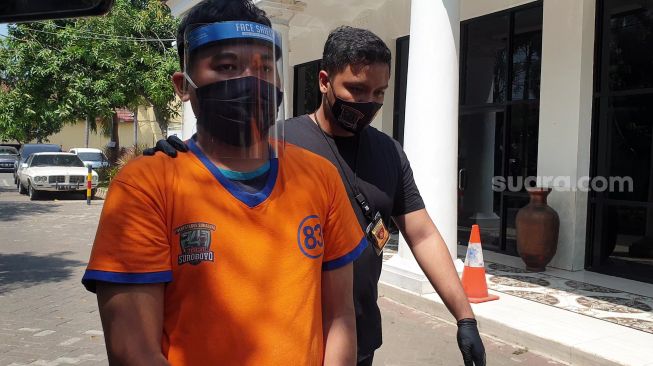 Gilang Aprilian Nugraha (22) yang membungkus korbannya dengan kain jarik berkedok tugas penelitian dan riset saat diarak menuju tahanan Mapolrestabes Surabaya, Sabtu (8/8/2020). [Suara.com/Arry Saputra]