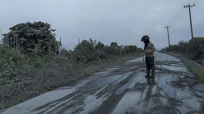 Warga membersihkan jalan yang dipenuhi debu vulkanik pascaerupsi Gunung Sinabung di Desa Sigarang-garang, Karo, Sumatera Utara, Sabtu (8/8/2020). [ANTARA FOTO/Sastrawan Ginting]