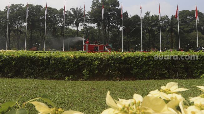 Petugas pemadam kebakaran menyemprotkan cairan disinfektan di area komplek Gedung DPR/MPR RI, Jakarta, Minggu (9/8/2020). [Suara.com/Angga Budhiyanto]