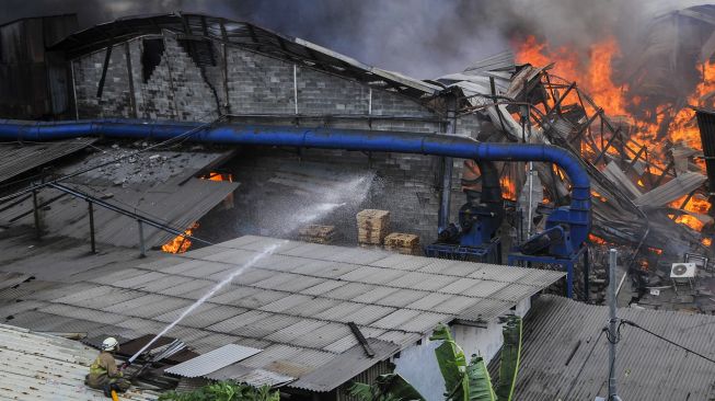 Petugas mencoba memadamkan kebakaran di pabrik mebel di kawasan Cakung, Jakarta Timur, Minggu (9/8/2020). [ANTARA FOTO/ Fakhri Hermansyah]