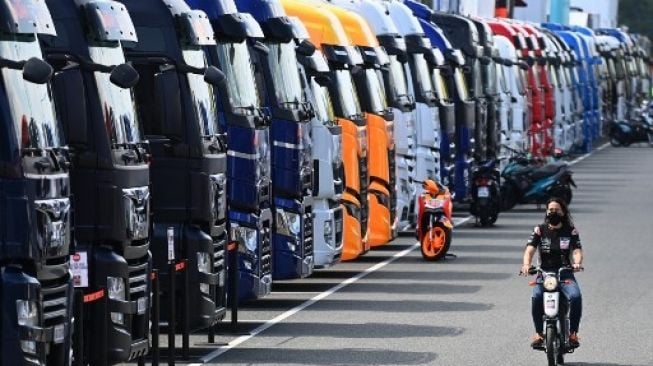 Seorang anggota tim MotoGP dengan memakai masker melintasi paddock saat sesi latihan di MotoGP Republik Ceko di sirkuit Brno. JOE KLAMAR / AFP