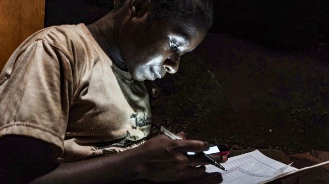 Hagar Kegiye (12 tahun) mengerjakan tugas sekolah di kios layanan internet, Kota Jayapura, Papua, Minggu (9/8/2020). [ANTARA FOTO/Indrayadi TH]