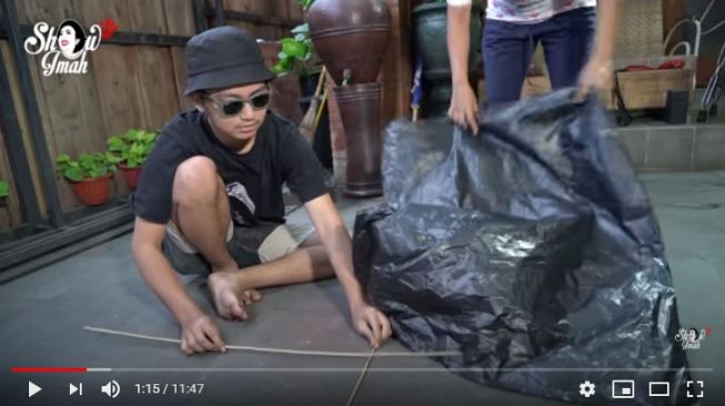 Putra Shoimah sedang mengukur plastik dengan kerangka layangan yang akan dibuat di rumah. - (YouTube/ Shoimah)