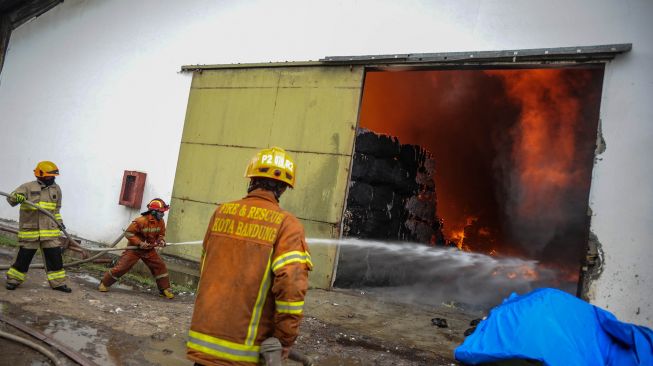 Petugas pemadam kebakaran berusaha memadamkan api yang membakar salah satu gudang pabrik kapas di Cipadung, Bandung, Jawa Barat, Selasa (11/8/2020).  [ANTARA FOTO/Raisan Al Faris]