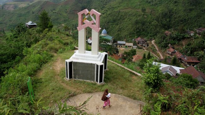 Warga melintas di dekat Tugu Anti Rokok di Desa Bone-Bone, Kabupaten Enrekang, Sulawesi Selatan, Senin (10/8/2020). [ANTARA FOTO/Arnas Padda]